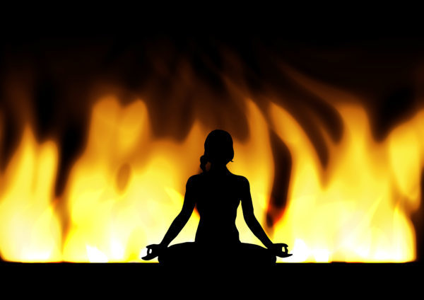 気功・ヨガ・瞑想する女性シルエットと炎の背景